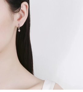 Detail of 925 silver hoop earring with small pink heart charm shown on ear