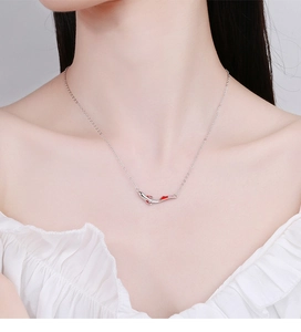 Close-up of 925 sterling silver koi fish pendant necklace with red enamel on a model