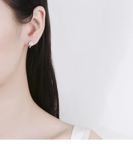 Gros plan de boucles d'oreilles fleur à cinq pétales en argent S925 sur un mannequin