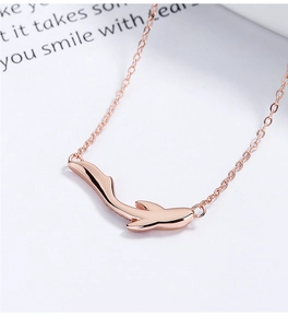 Macro shot of rose gold koi fish pendant with smooth mirror finish and cross chain link