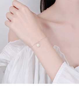Detailed view of a S925 sterling silver daisy bracelet on a female wrist in soft lighting