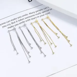 Detail of 925 sterling silver long tassel earrings with metallic balls in gold and silver