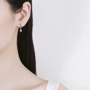 Minimalist 925 silver hoop earrings with a small red heart pendant on female model