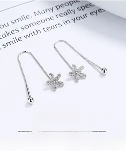 Macro detail of 925 sterling silver flower earrings with elegant tassel and box chain