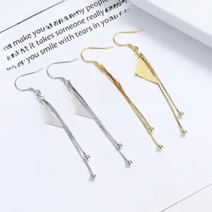 Detail of geometric silver and gold tassel earrings with long chain and metal beads