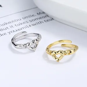 Detailed view of silver and gold heart rings with braided adjustable bands on card