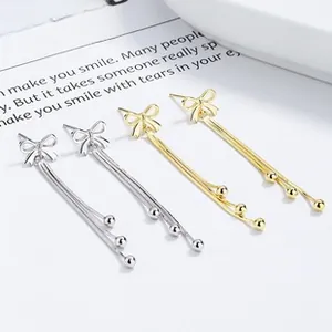 Detailed view of 925 silver and gold bow tassel earrings on elegant display cards