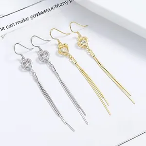 Détail de boucles d'oreilles cœur à pompon en argent 925 doré et argenté avec zircon
