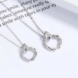 925 silver couples necklaces with thorn ring pendants on an elegant card background