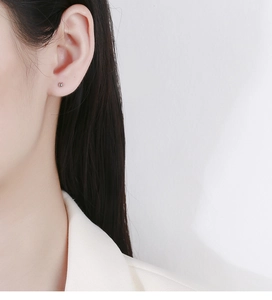 Gros plan d'une boucle d'oreille minimaliste en argent 925 sur une oreille de femme