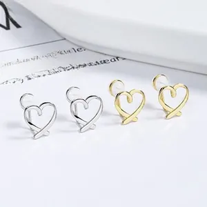 Minimalistische Herz-Ohrclips in Gold und Silber für Ohren ohne Löcher auf einem Teller
