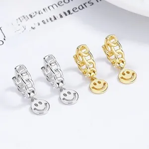 Detailed close-up of gold and silver hoop earrings featuring smiling face pendants