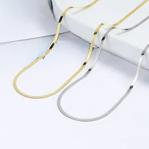 Macro detail of flat gold and silver snake chains on a minimalist white display