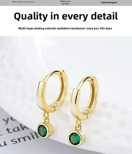 Macro detail of gold S925 sterling silver hoop earrings with round green gemstones
