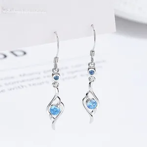 Detailed view of silver drop earrings with blue cubic zirconia on white display card