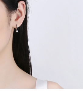 Close-up of 925 sterling silver hoop earrings with round clear zircon pendant on model