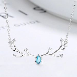 Detail of silver reindeer antler necklace with blue teardrop gemstone and white zircons