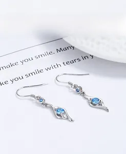 Macro detail of 999 sterling silver drop earrings with elegant blue zircon stones