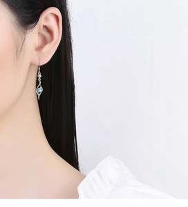 Detail of silver sterling ear hook with a blue cubic zirconia on a model ear