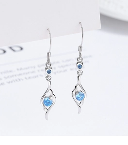 Macro shot of silver drop earrings featuring bright blue zircons and curved line design