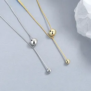 Macro detail of Y-shaped silver and gold bead necklaces with polished metallic finish