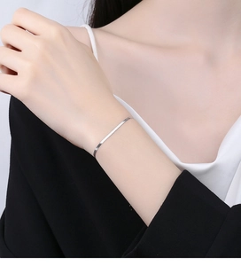 Close-up of minimalist silver flat snake bone chain bracelet worn by a model