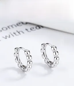 Macro detail of 925 sterling silver beaded hoop earrings with a polished metallic finish