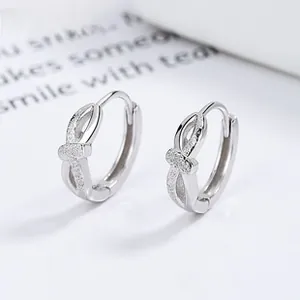 Macro shot of 925 sterling silver hoop earrings with frosted sand texture crossover knot