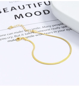 Detail of gold herringbone snake chain bracelet with heart charm and lobster clasp