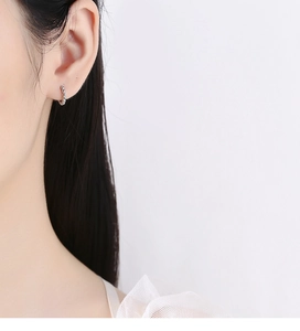 Close-up detail of silver beaded hoop earrings showing the round polished metal texture