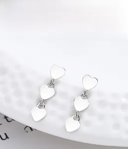 S925 sterling silver triple heart earrings with multi-layer plating on white textured plate