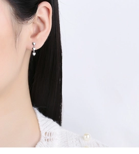 Detail of silver triple heart drop earrings worn by model showing style and scale