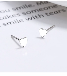 Macro shot of S925 sterling silver heart stud earrings with visible authenticity hallmark