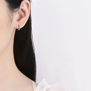 Minimalist 925 sterling silver beaded hoop earrings worn by a model in a side view