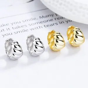 Gros plan de boucles d'oreilles créoles torsadées dorées et argentées style croissant