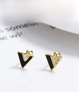 Detailed view of asymmetric gold plated 925 silver V-shaped studs with black enamel finish