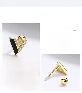 Detailed close-up of gold V-shaped stud earrings with black enamel and crystal inlay