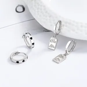 Detail of 925 sterling silver hoop earrings featuring black enamel hearts and engraved tag