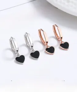 Détail de boucles d'oreilles en argent 925 et or rose avec pendentifs cœurs noirs