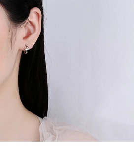 Close-up of polished 925 silver lightning bolt hoop earrings worn by a model