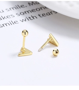 Macro detail of V-shaped gold screw-back earrings with polished metallic texture
