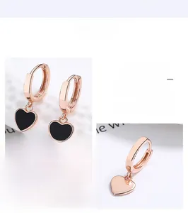 Détail de boucles d'oreilles cœur en or rose avec émail noir et finition polie