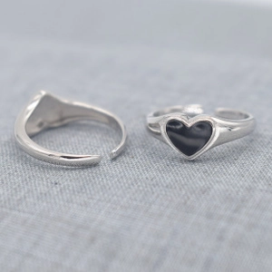 Close-up of adjustable silver rings with sleek black heart details and metal finish