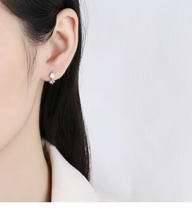 Close-up of a 925 silver star earring with a dangling cubic zirconia on a model ear