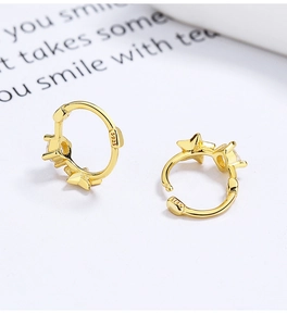 Macro detail of gold S925 sterling silver hoop earrings with star charm and cubic zirconia