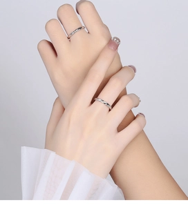 Detailed close-up of Mobius style silver couple rings with twisted design and zircon inlay