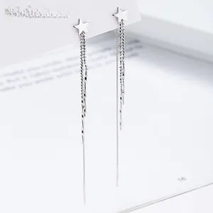 Detailed view of silver star tassel earrings with long chains on a stylish display card