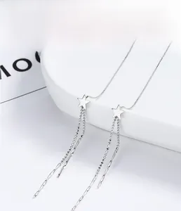 Macro detail of 925 sterling silver star fringe earrings on a white porcelain tray