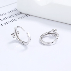 Boucles d'oreilles créoles en argent 925 et zircon sur fond blanc minimaliste