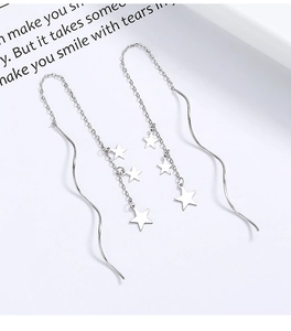 Macro detail of 925 sterling silver star tassels and wave chain dangling earrings